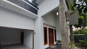 Una casa moderna con un patio empedrado, una puerta de madera y una planta en maceta.