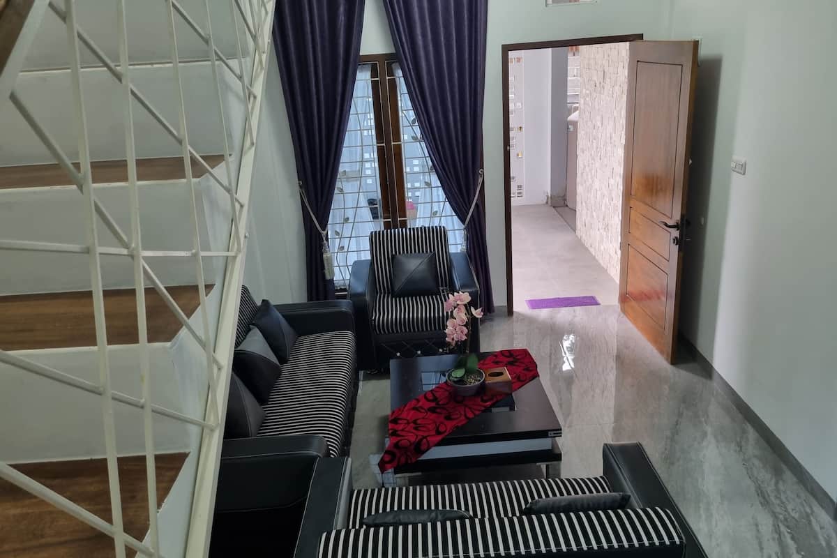 A modern living room with a sofa, a striped chair, a coffee table with a red cloth, and a staircase.