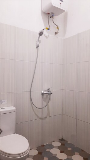 A small, tiled bathroom with a shower, toilet, and a wall-mounted heater. - Wafaby Guest House (Payakumbuh)