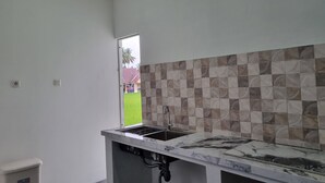 A kitchen with a marble countertop, a sink, and a tiled backsplash. - Wafaby Guest House (Payakumbuh)