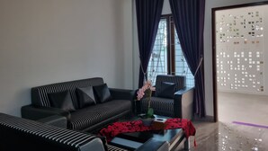 A modern living room with a black and white striped sofa, a black armchair, and a coffee table with a red patterned table runner. - Wafaby Guest House (Payakumbuh)