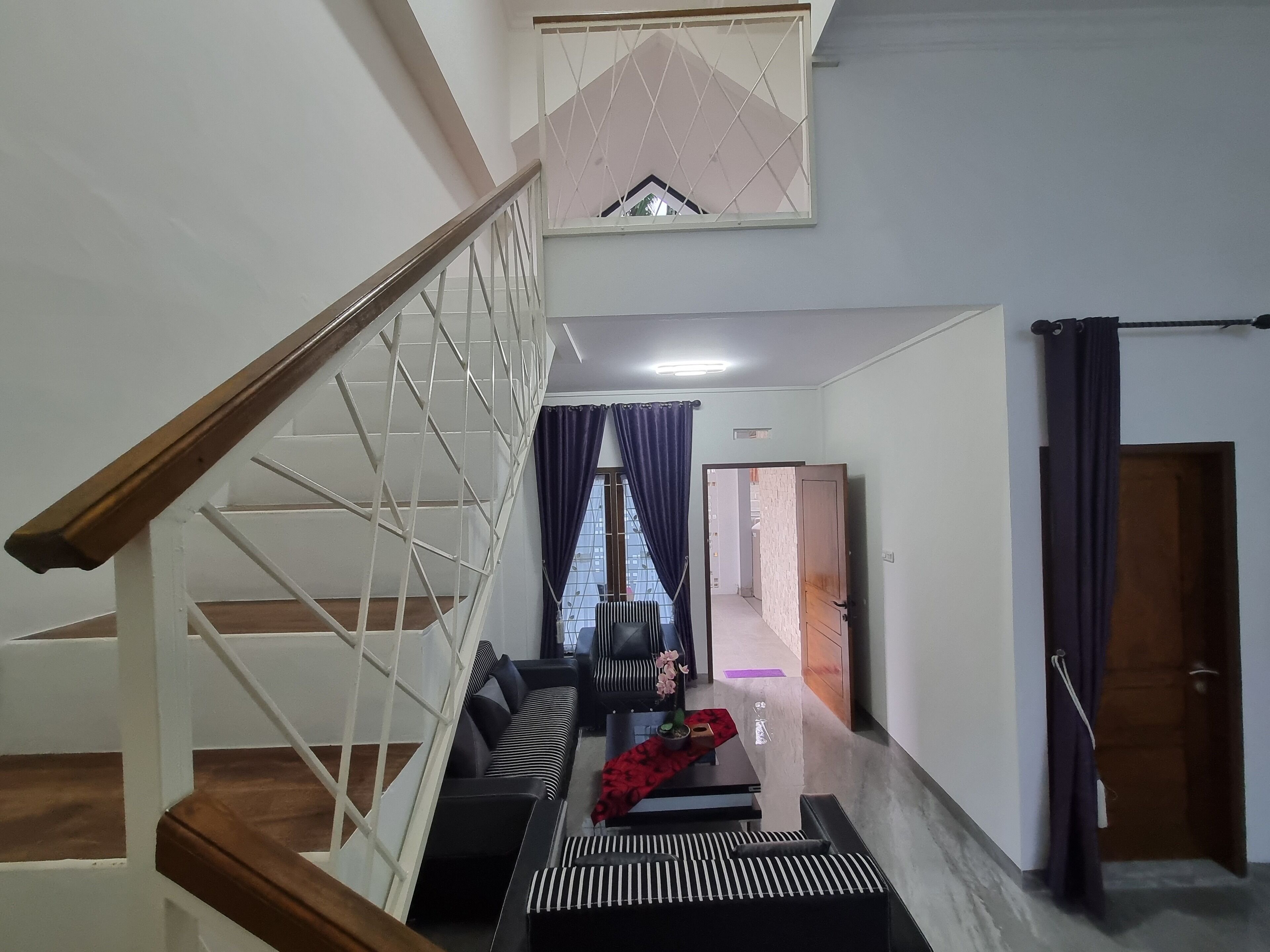 Un escalier avec une rampe en bois et des balustrades blanches, menant à un palier où se trouvent un canapé et une petite table.