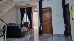 A modern living room with a staircase, a sofa set, and a wooden door. - Wafaby Guest House (Payakumbuh)