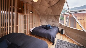 A cozy tent-style room with two beds, a wooden slat wall, and a large window offering a view of the outdoors. - Dots by Dot Glamping Suite 001 (Fujikawaguchiko)