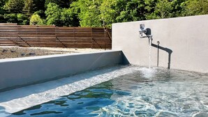A swimming pool with clear water, a faucet, and a wooden fence in the background. - Dots by Dot Glamping Suite 001 (Fujikawaguchiko)