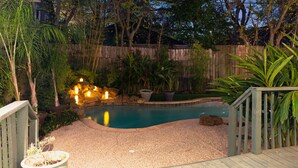 A backyard with a swimming pool, wooden deck, and potted plants. - 3BR The Poseidon! Aquatic Dream Pool in Montrose! (Houston)