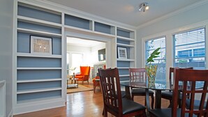 A dining area with a glass table surrounded by wooden chairs, white shelving units, and a vase with a plant. - 3BR The Poseidon! Aquatic Dream Pool in Montrose! (Houston)
