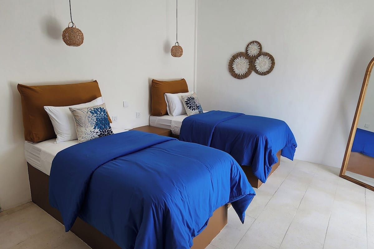 A bedroom with two beds, a large mirror, and decorative wall art.