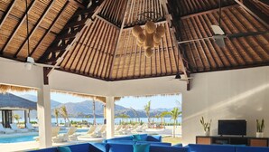 A modern lounge area with blue sofas and a pool view. - Mocean Beach Resort (Sumbawa Barat)