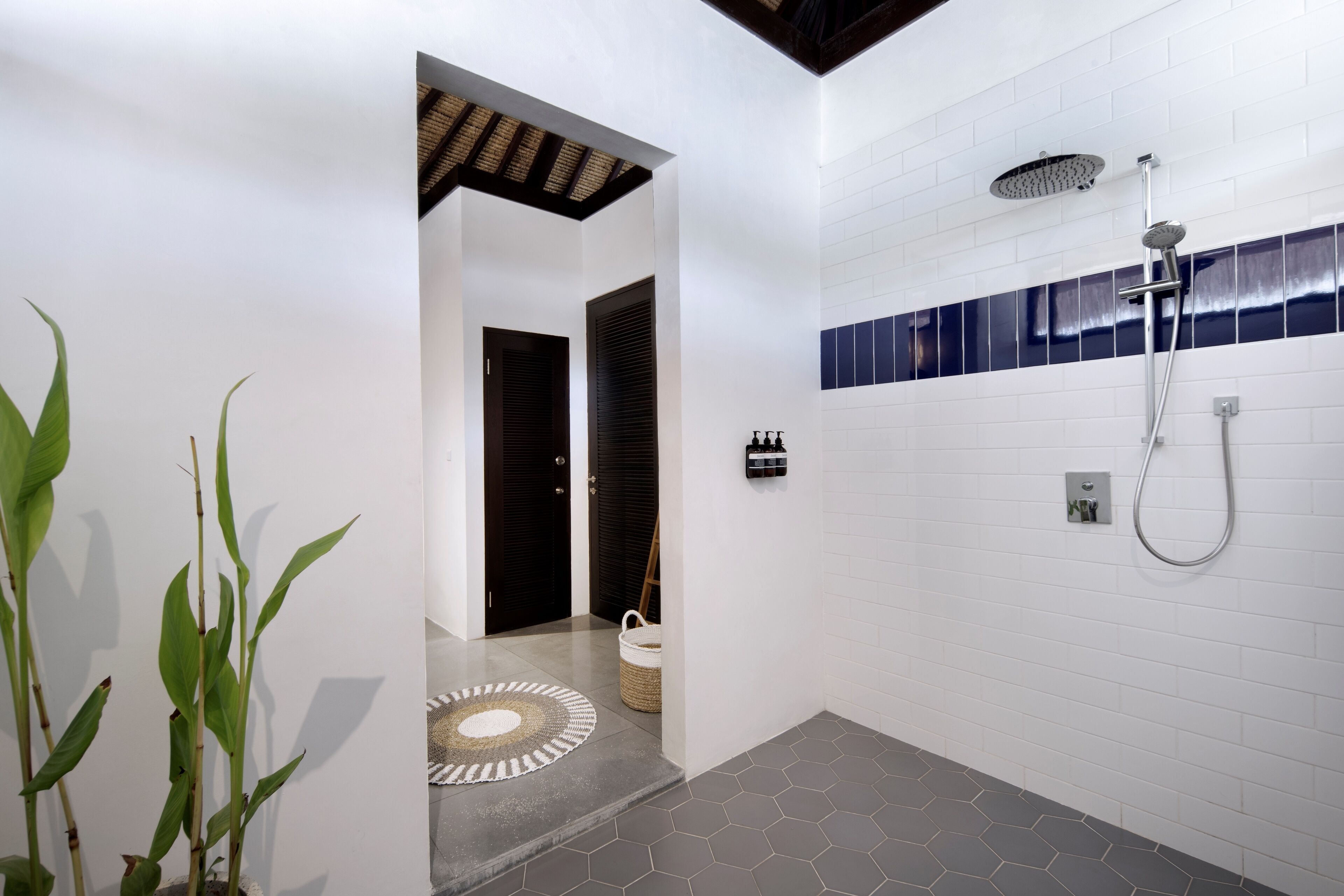 Un baño moderno con ducha, pared con azulejos y suelo estampado.