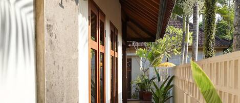 A covered outdoor corridor with a stone wall, wooden steps, and potted plants.