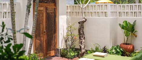 A small, private garden with a wooden door, a bench, and a potted plant.