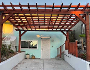 Un patio couvert agrémenté d’une pergola en bois, d’une porte blanche et d’une fenêtre.