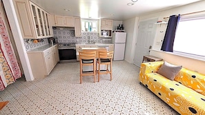 A compact kitchen with a dining area, a refrigerator, and a patterned floor.