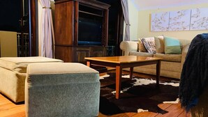 Een woonkamer met een houten salontafel, een bank en een grote houten kast.