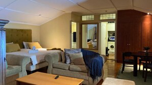 Hotelkamer met een bed, een bank en een kleine tafel. Er is een spiegel, een raam en een deur naar een badkamer.