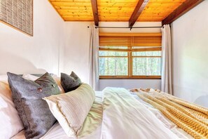 A room with a bed, a window with blinds, and a wooden ceiling. - Tranquil Grove | Hot Tub | Game Room | Fire Pit (Lake Ariel)