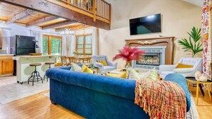A spacious living area with a blue sofa, a fireplace, and a television. - Tranquil Grove | Hot Tub | Game Room | Fire Pit (Lake Ariel)