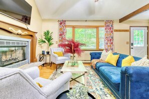 A living room with a fireplace, a blue sofa, a white armchair, and a coffee table.