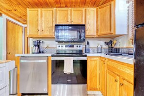 A kitchen with wooden cabinets, a microwave, a stove, and a dishwasher.