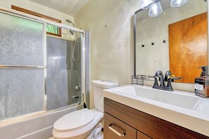 Une salle de bain équipée d’une douche, de toilettes, d’un lavabo et d’un miroir.