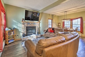 A living room with a stone fireplace, leather sofa, and a television mounted above it.