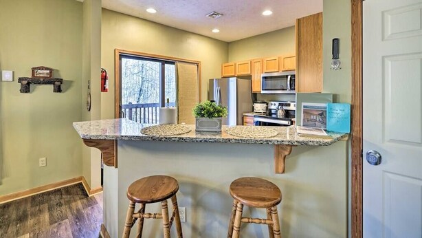 A kitchen with a granite countertop, wooden stools, a microwave, and a refrigerator. - HOT TUB | 4 Min Dr to Camelbeach (Tannersville)