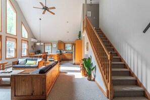 A spacious living area with a high ceiling, a staircase, and a kitchen in the background. - Dee Grove Retreat | Game Area | Open Concept | 4 BDR Close to Skiiing, Lake (Albrightsville)