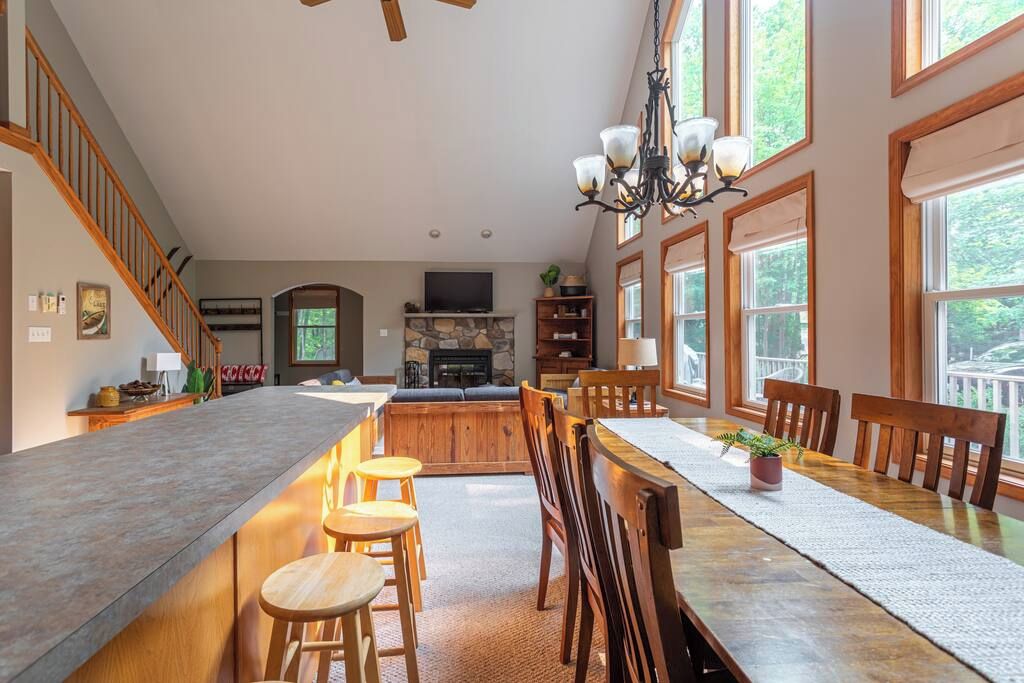 A spacious kitchen with a long island, wooden chairs, and a dining table.