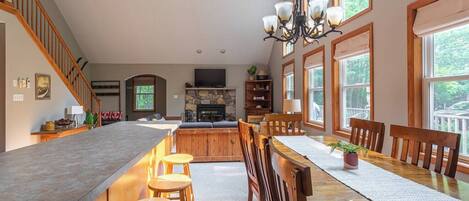 A spacious kitchen with a long island, wooden chairs, and a dining table.