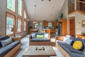 A spacious living room with a sofa set, a coffee table, and a dining area with a table and chairs. - Dee Grove Retreat | Game Area | Open Concept | 4 BDR Close to Skiiing, Lake (Albrightsville)