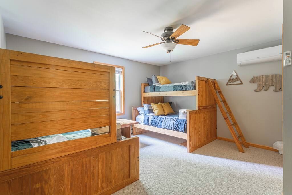 Un dormitorio con literas, un armario de madera y un ventilador de techo.