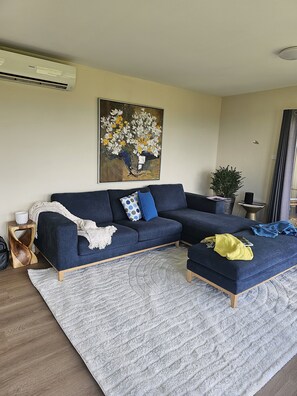 Relax in this inviting living room with a comfortable sofa, abstract art, and a cozy throw blanket.