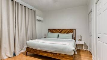 Una camera da letto con un letto di legno, biancheria bianca, un comodino, una ventola a soffitto e un armadio.