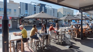 Uma área externa com mesas, cadeiras, guarda-sóis e um letreiro para 'Oyster Bar & Eatery'.