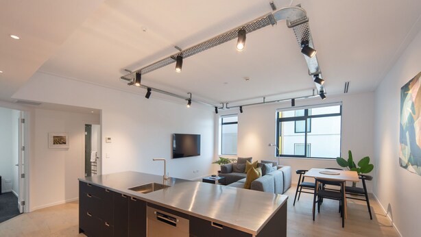 Uma cozinha moderna com ilha central, eletrodomésticos embutidos e iluminação pendente.