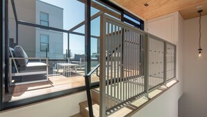 Uma escadaria moderna com guarda-corpo de vidro, que leva a um deck externo com área de estar.