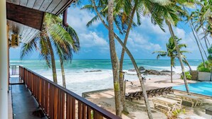 A beachside view with a wooden deck, lounge chairs, and a swimming pool. - Amor Beach Unawatuna (Unawatuna)