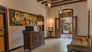 A spacious lobby with a wooden bench, a television on a cabinet, and a large painting on the wall. - Amor Beach Unawatuna (Unawatuna)