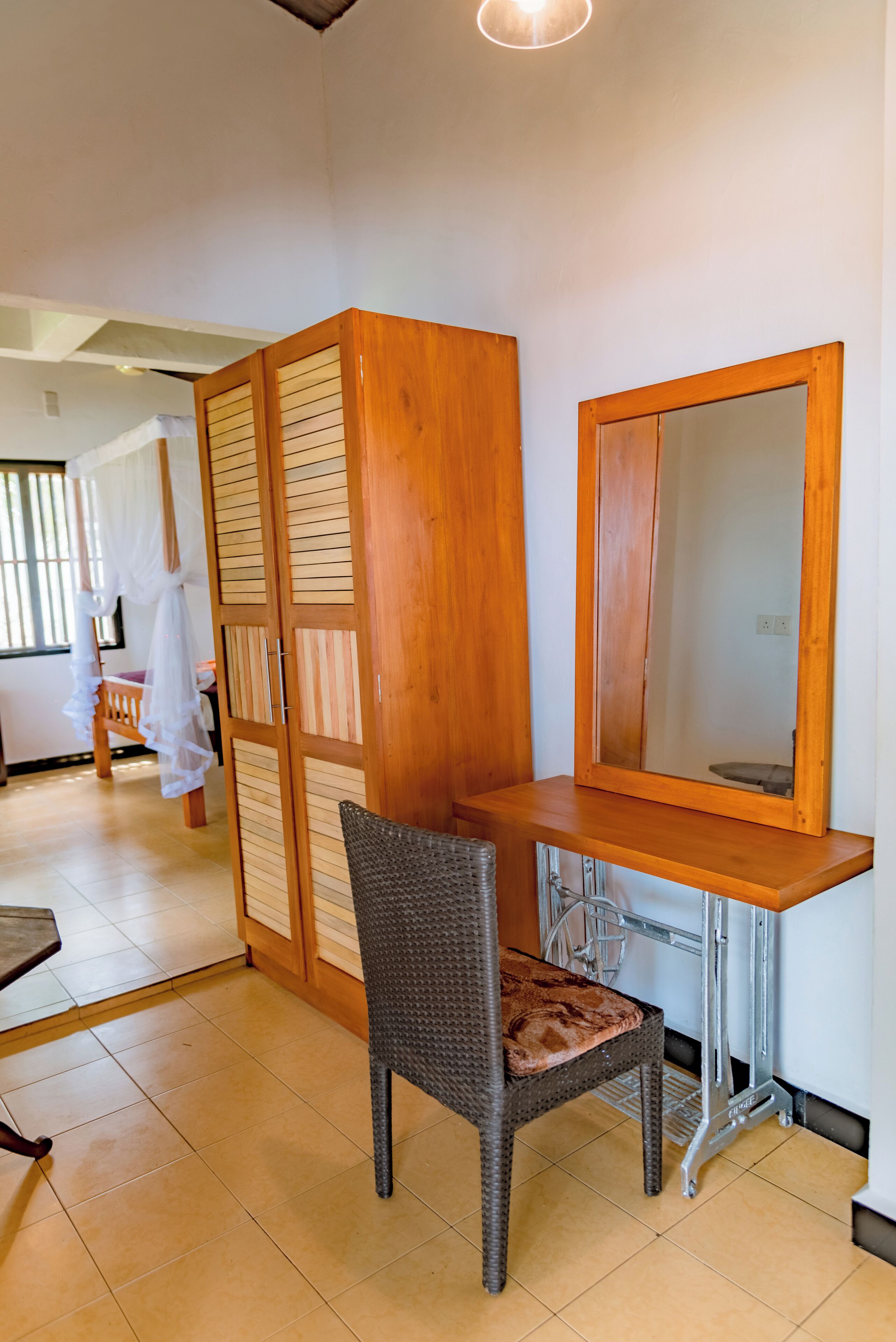 A room with a wooden desk, a chair, a large mirror, and a partition with a ruffled curtain.