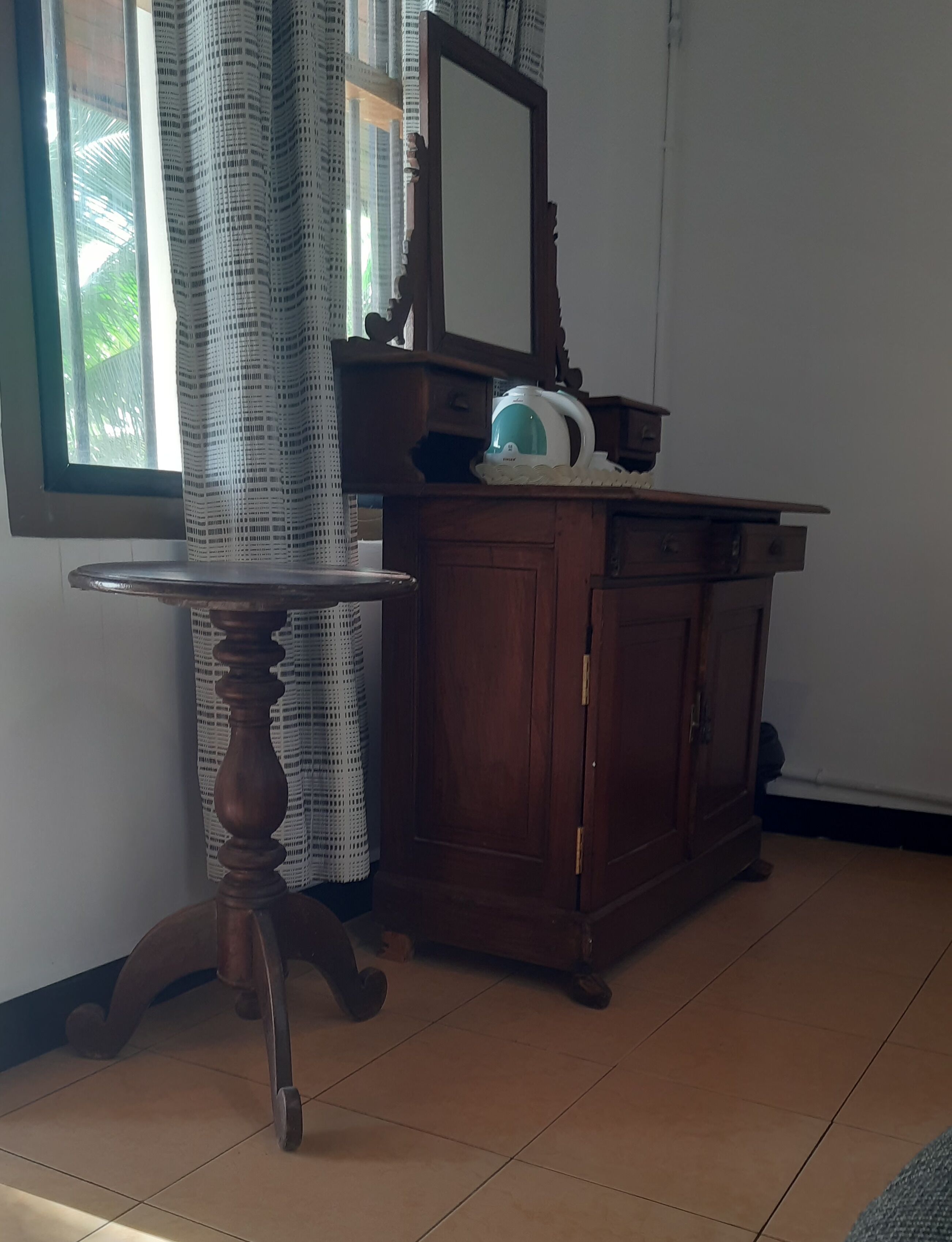 Ein Zimmer mit einem Holzkabinett, einem runden Tisch und einem Spiegel.