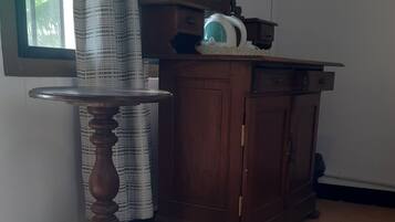 Ein Zimmer mit einem Holzkabinett, einem runden Tisch und einem Spiegel.