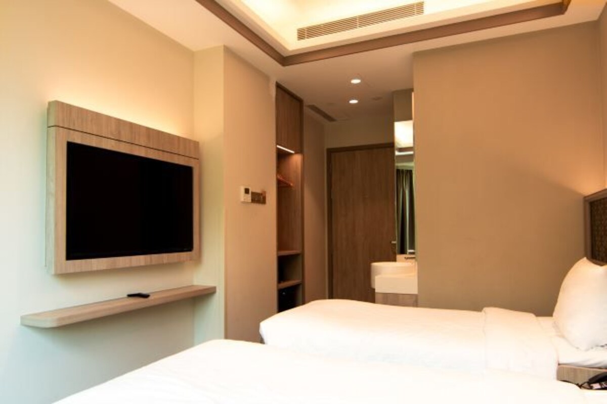 Une chambre d’hôtel équipée d’un téléviseur à écran plat fixé au mur, d’un lit, d’une table de chevet et d’une armoire.