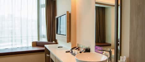 Un baño moderno con un lavamanos blanco grande, un espejo y un ventanal con cortinas.