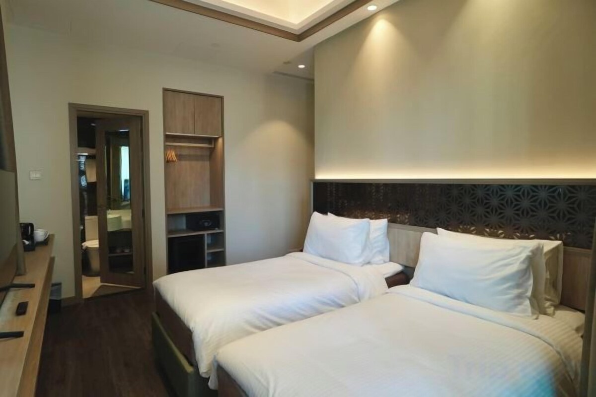 A hotel room with two beds, a walk-in closet, and a built-in shelf unit.