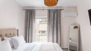 A hotel room with a bed, a headboard, a large mirror, and a view of the outside balcony.