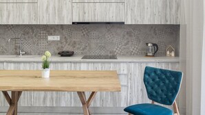 A modern kitchen with a wooden table, a blue upholstered chair, and a bench.