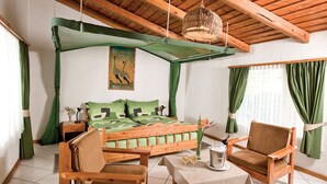 Una habitación con cama, muebles de madera, una mesa con bebidas y un cuadro en la pared.