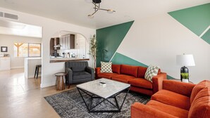 A modern living room with a sofa, coffee table, and a kitchen area in the background.