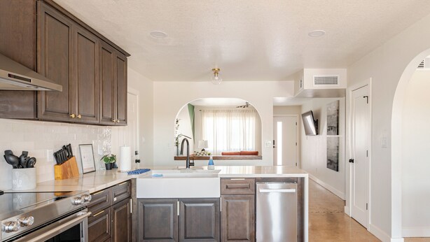 A modern kitchen with dark wooden cabinets, stainless steel appliances, and a central island.